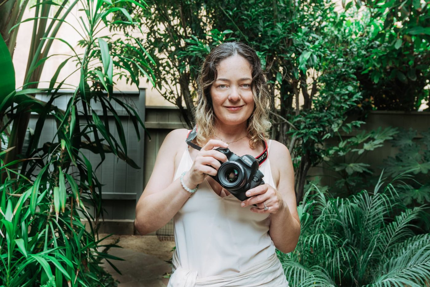 Simone Dib holding her camera in a green garden